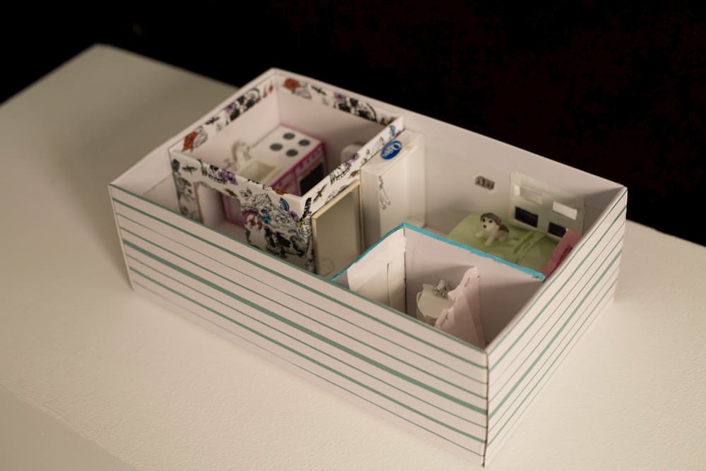 A box without the lid that shows a miniature apartment.