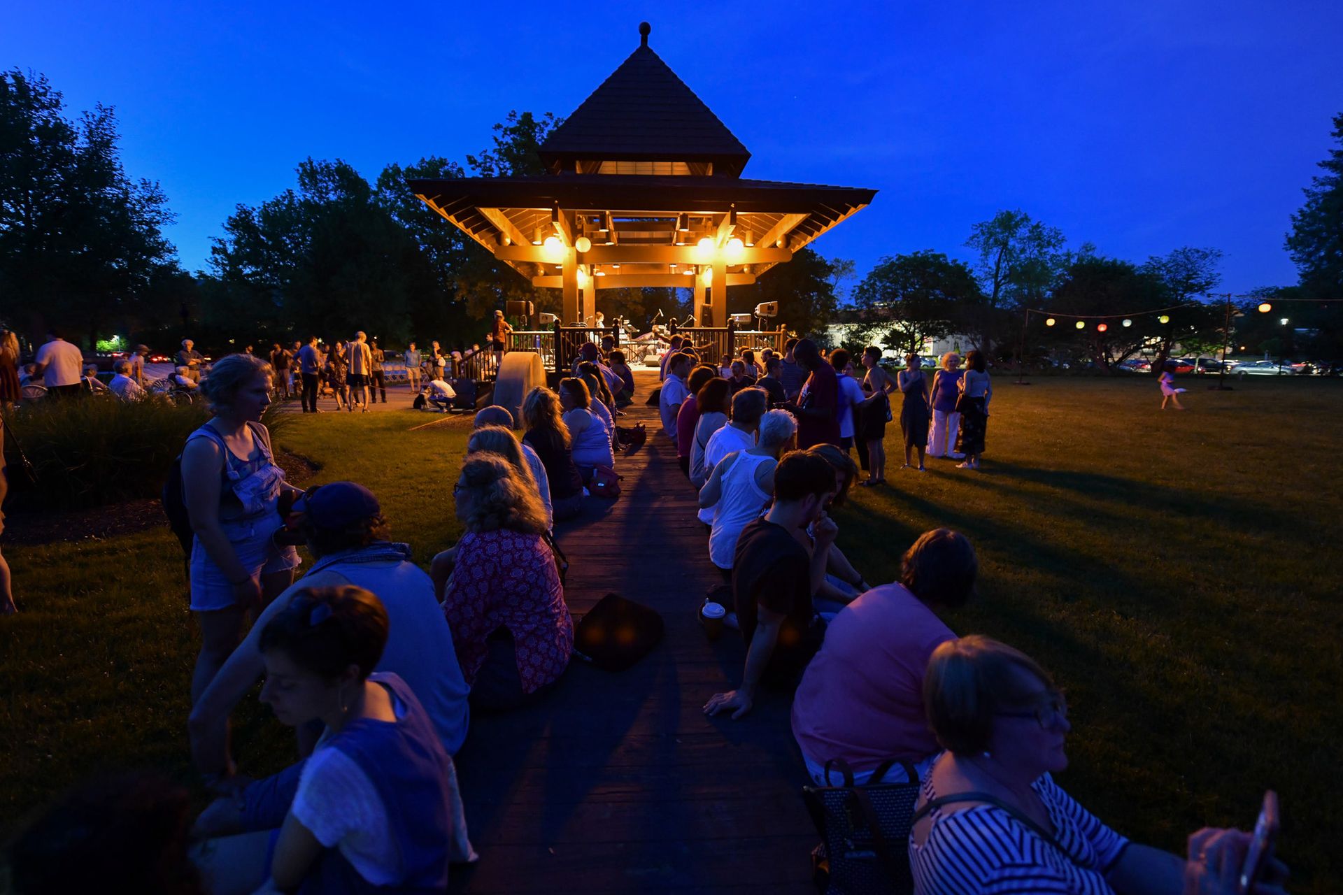 People sit on a ramp leading to a gazebo. 