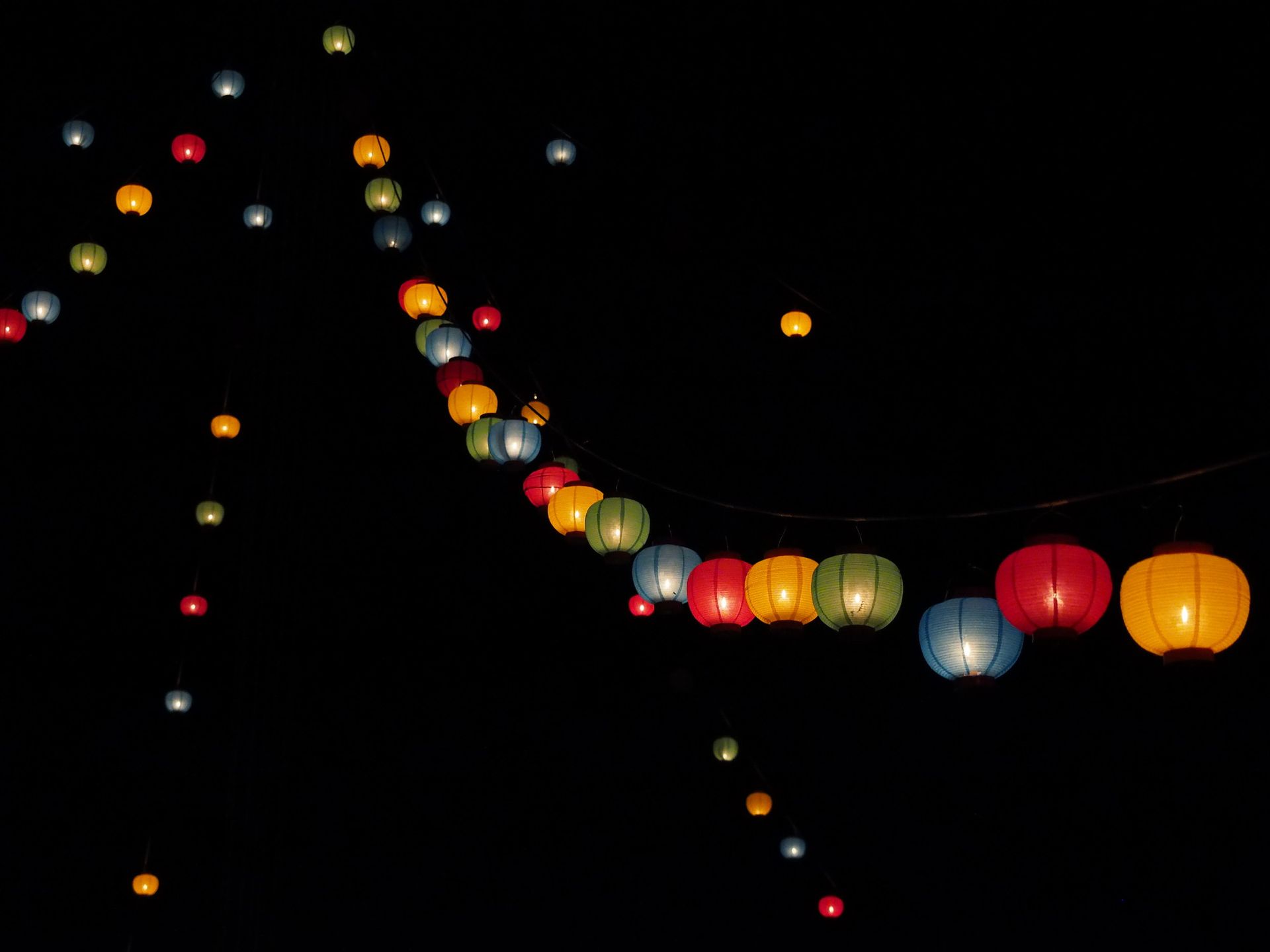 Lanterns hang from a tall tower at night.