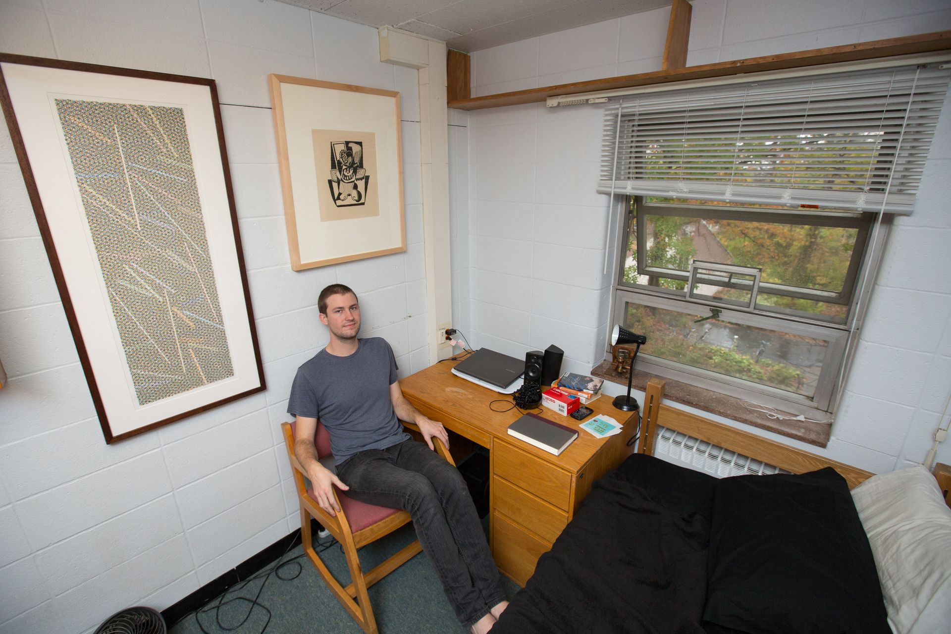 A boy sits next to two pieces of artwork