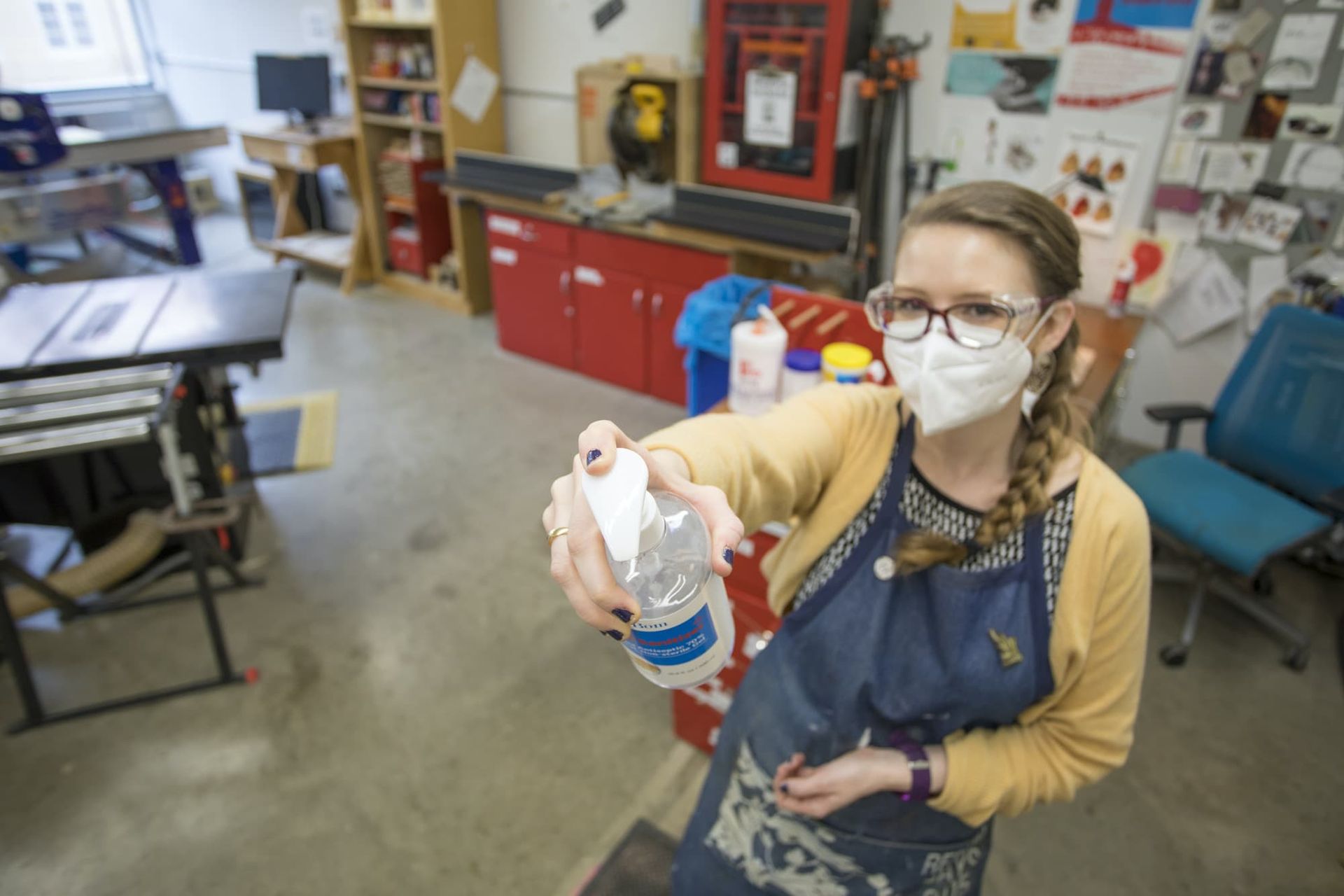 A woman pretends to give hand sanitizer to a camera lens.