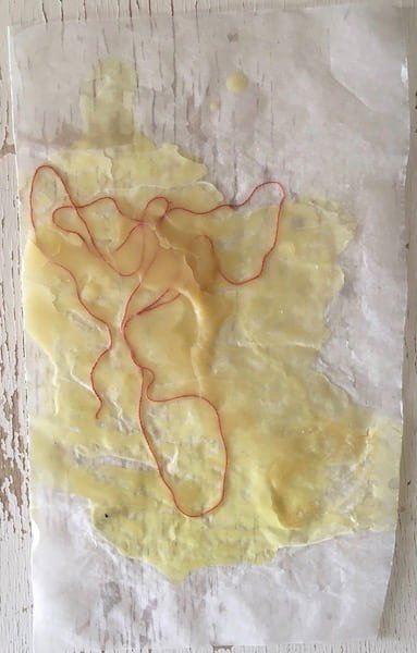 Wax on a sheet of paper with a string stuck in it.