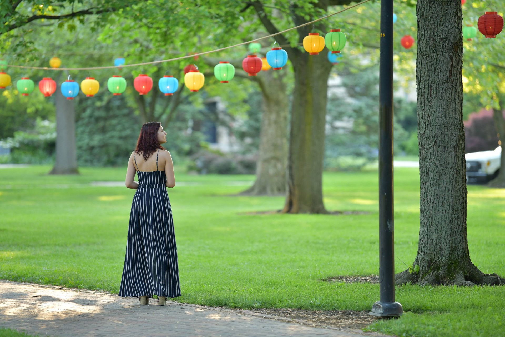 A girl stares at a lantern hanging from a rope.