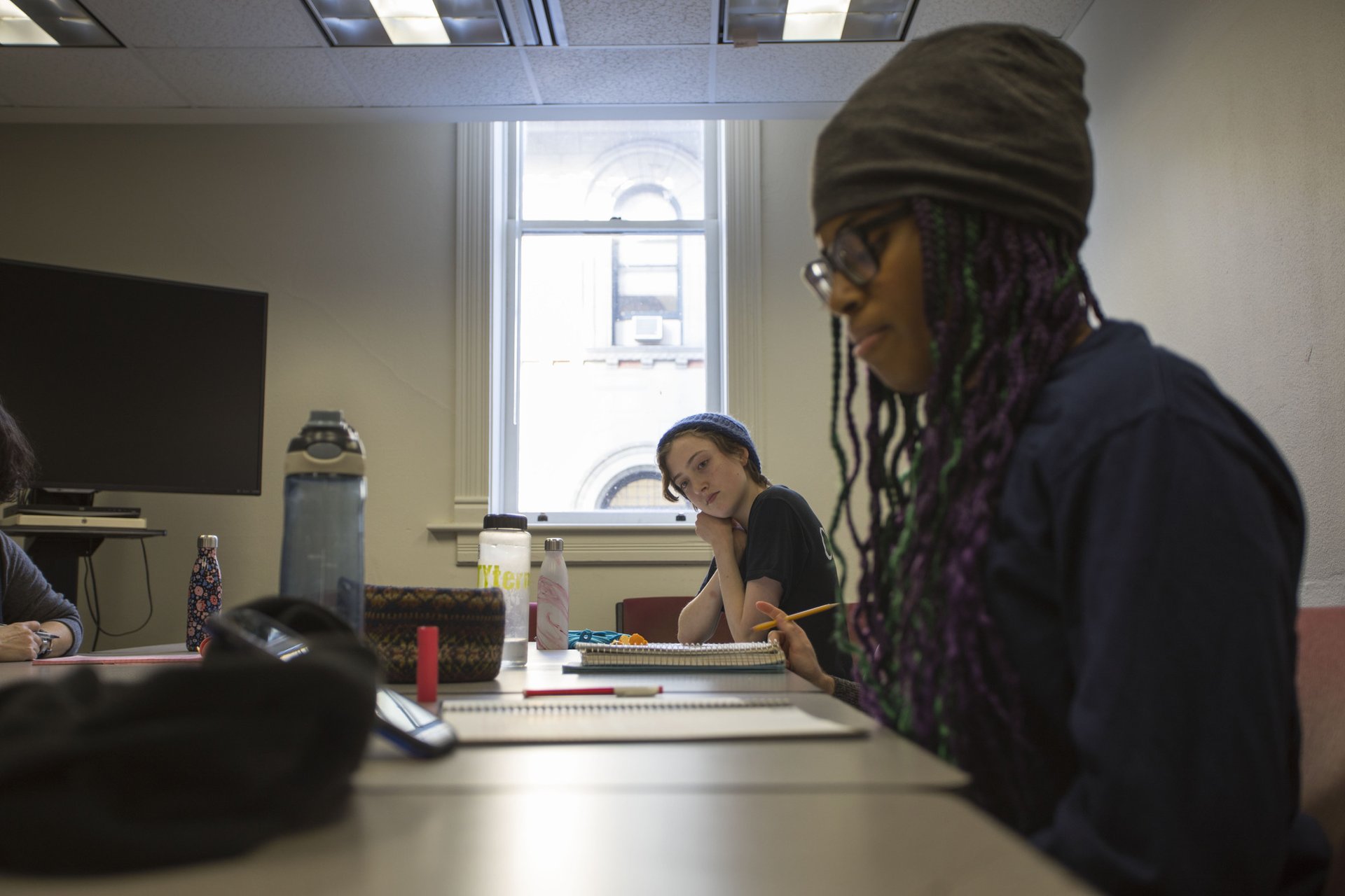 A girl claps her hands and listens to a student in a classroom.