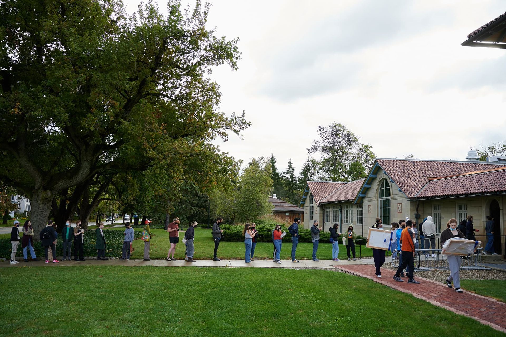 A long line of people stand in front of a art museum.