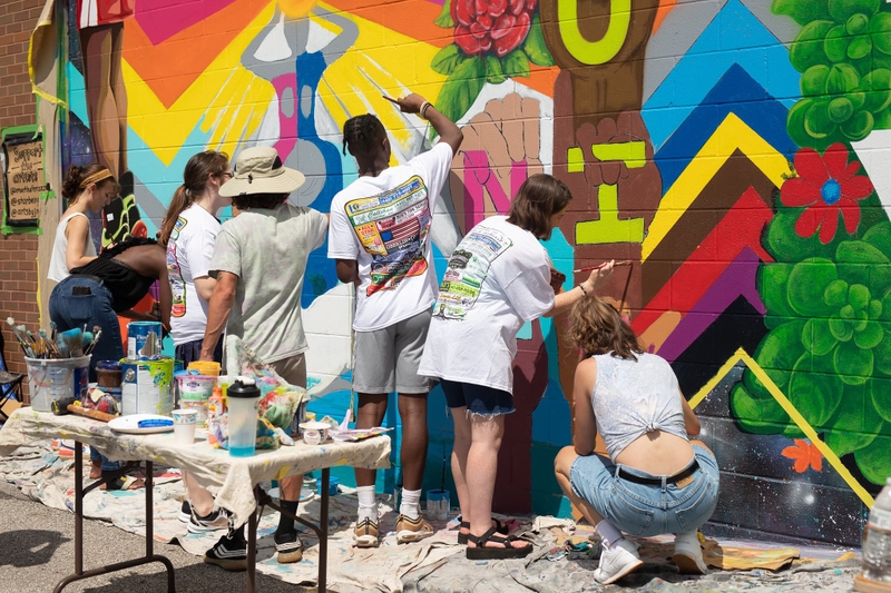A group of people paint a mural.