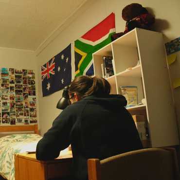 Flags and photos cover the walls of a small dorm room