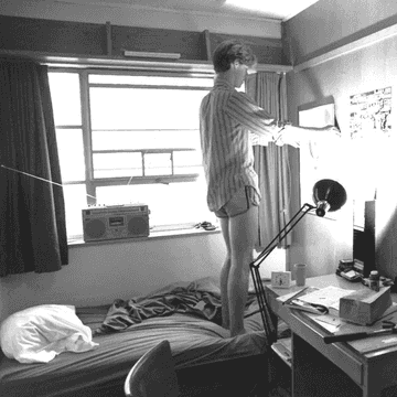 A student tapes music posters on his room walls.