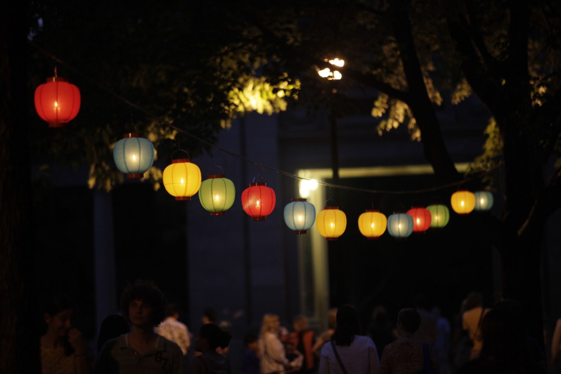People walk under lanterns at night.
