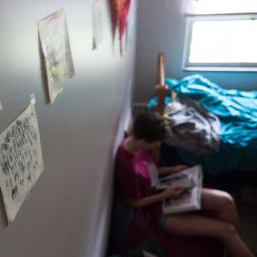 Drawings on paper napkins are tapped to a dorm room wall.