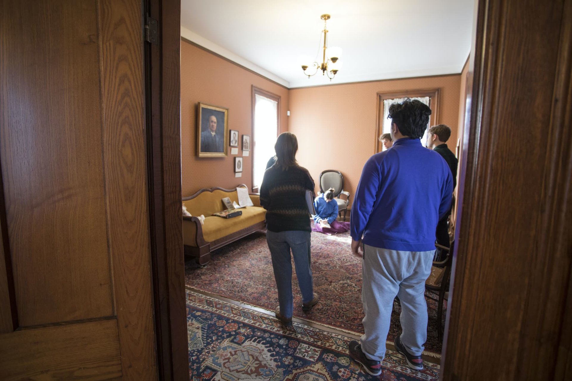 A group of students stand in a semi-circle during the tour of a century home.