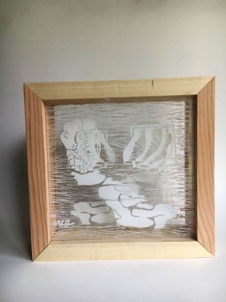 A wooden frame with etched figures on a clear sheet