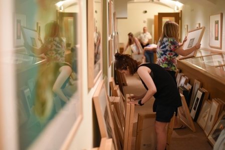 Students look through stacks of framed artwork.