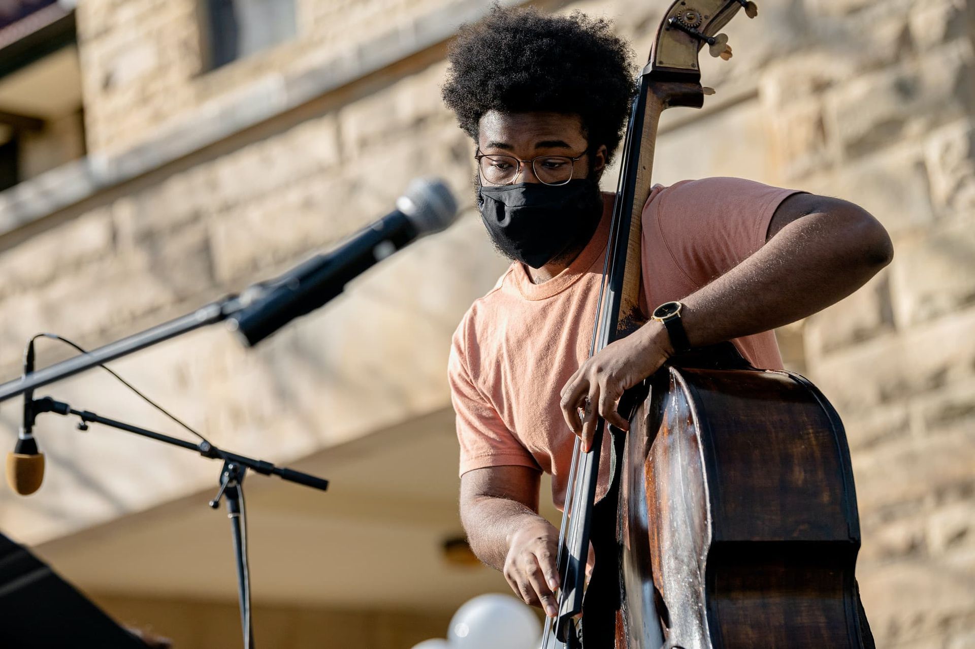 A young plays a cello at an outdoor concert.