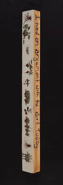 A long wooden stick with flowers on it has the words I had an argument with the dirt today written on the side.