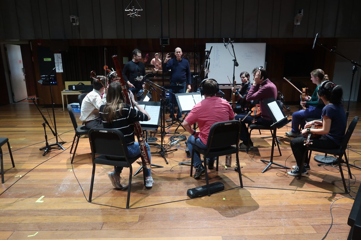 Students sit with musical instruments in a recording studio.