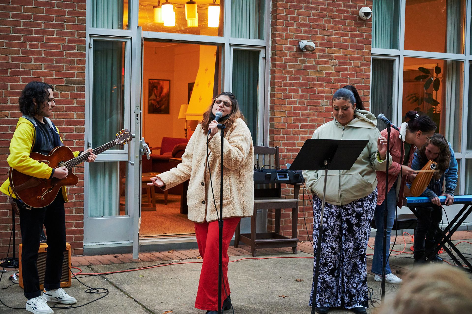 Two women sing into microphones with a band behind them.