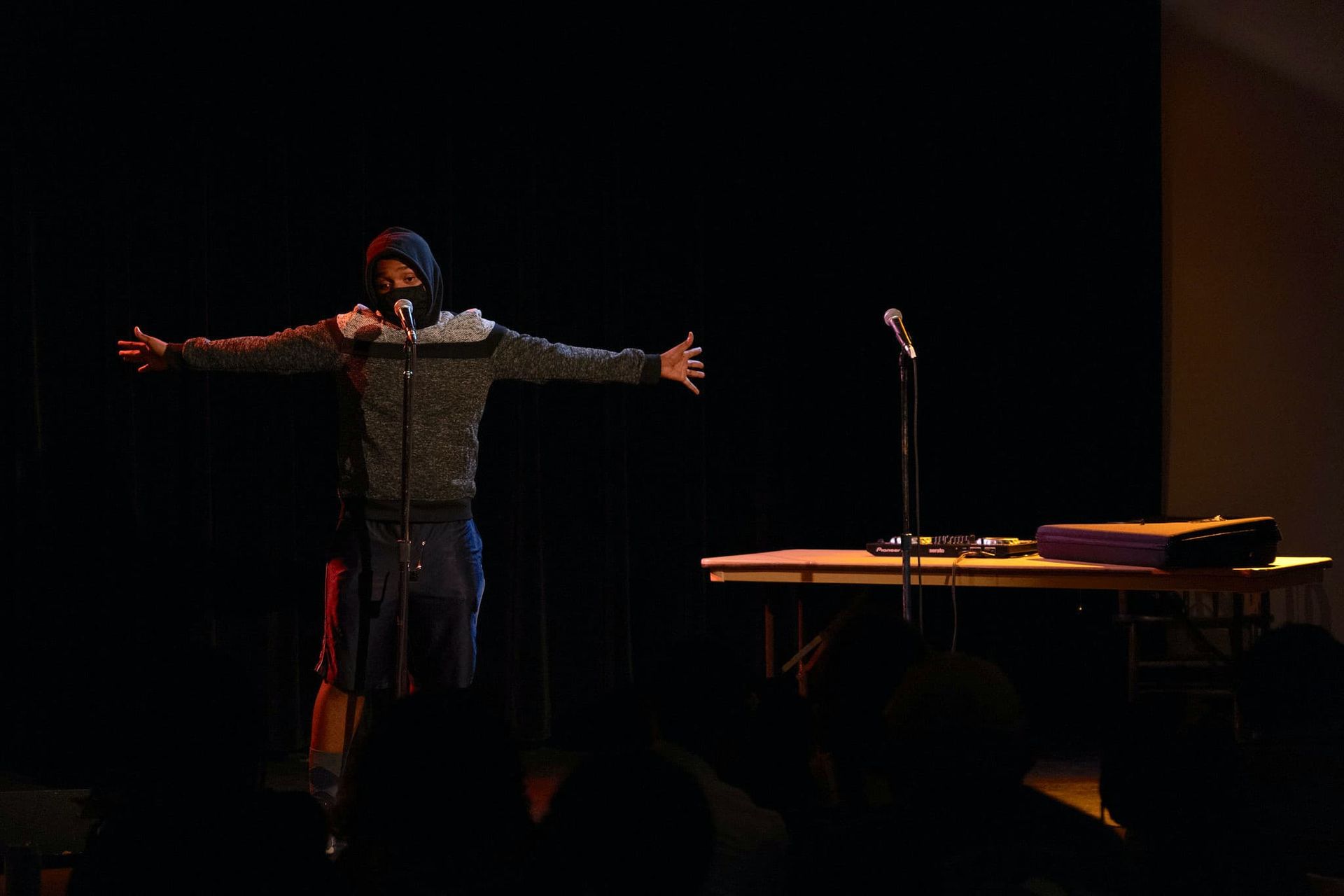 A man stretches his arms while speaking into a microphone.