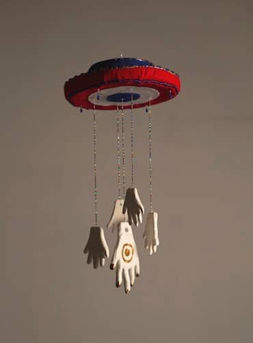 A felt and beaded chime with ceramic hands hanging on beaded strings