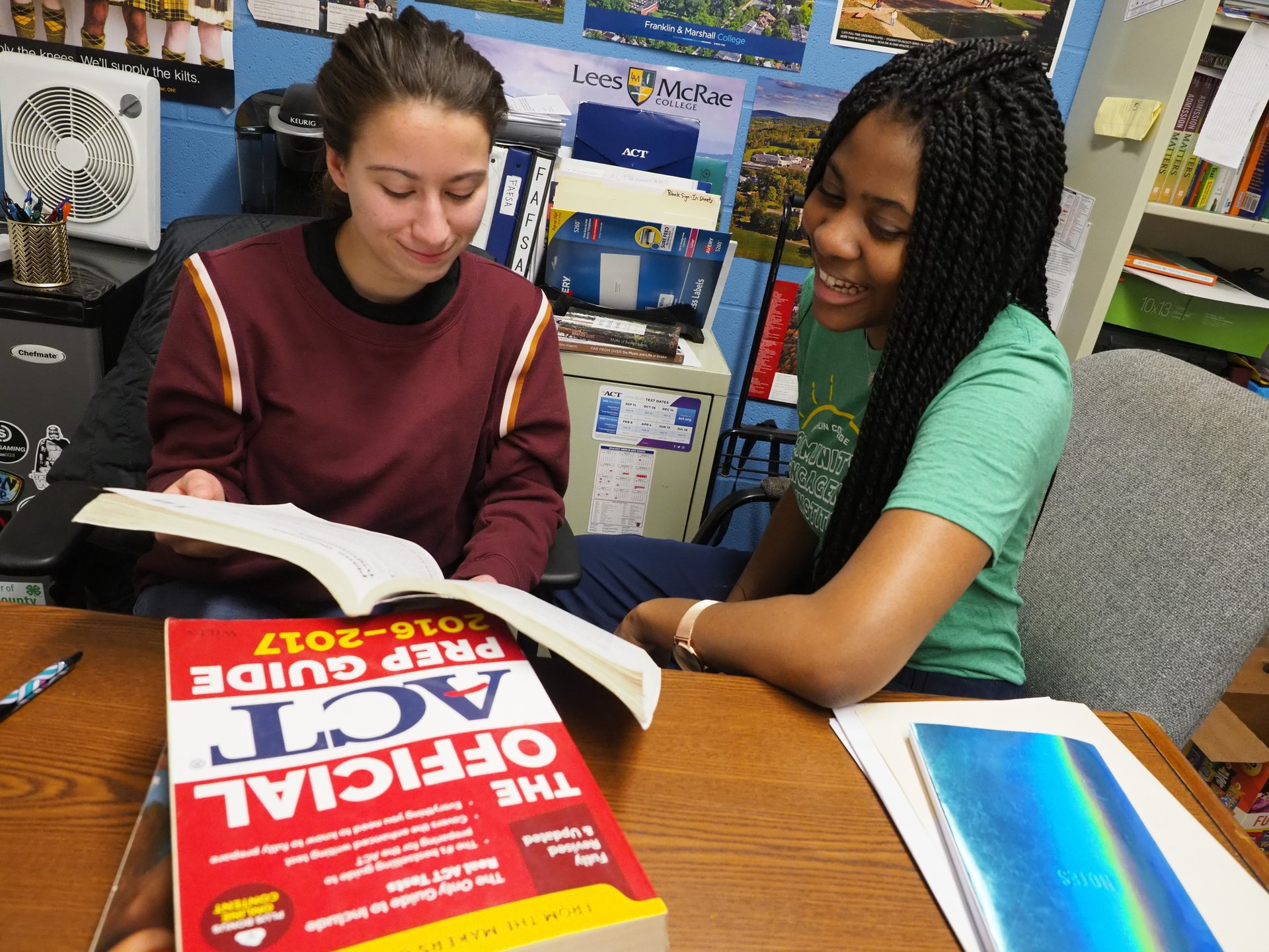 Two students look at a text book together.