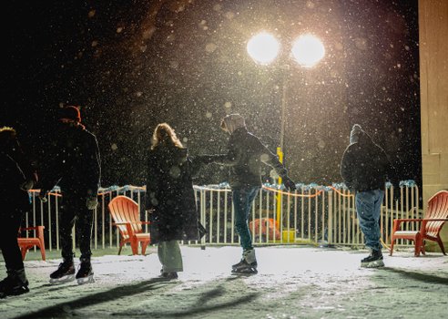 Students ice skate at night in an outdoor rink.