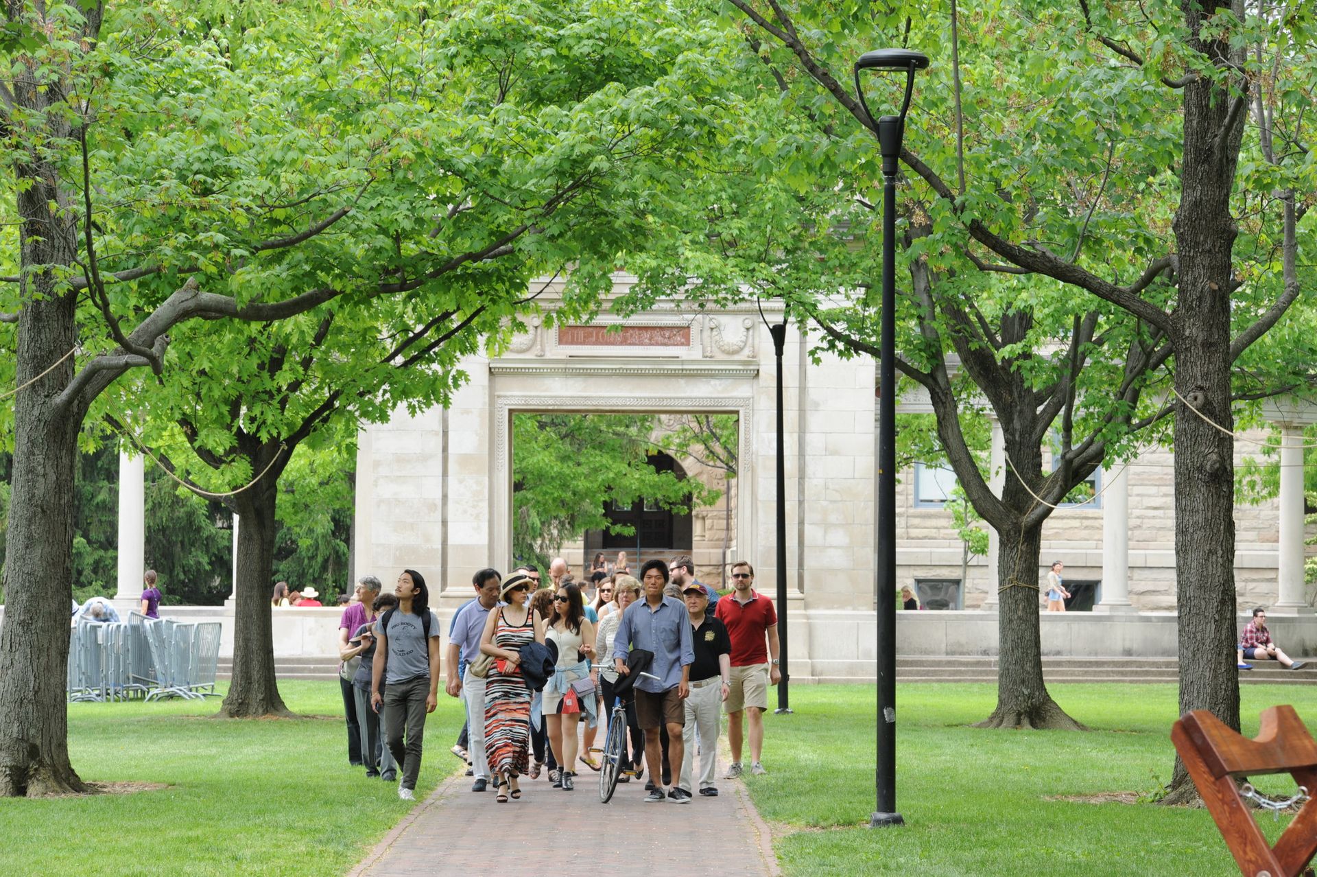 A group of people walk under a large brick arch.