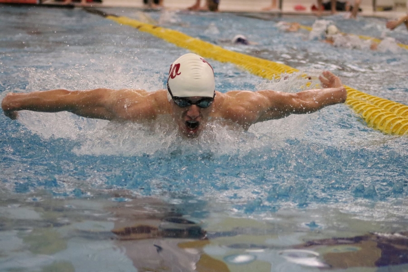 A male swim team member competes.