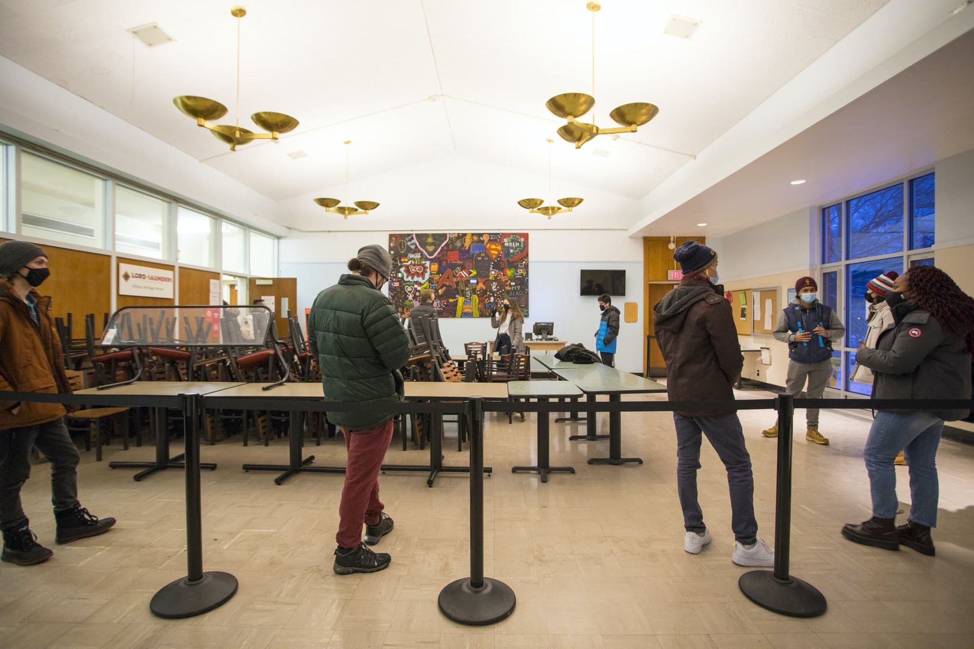 People stand in a line at a dining hall.