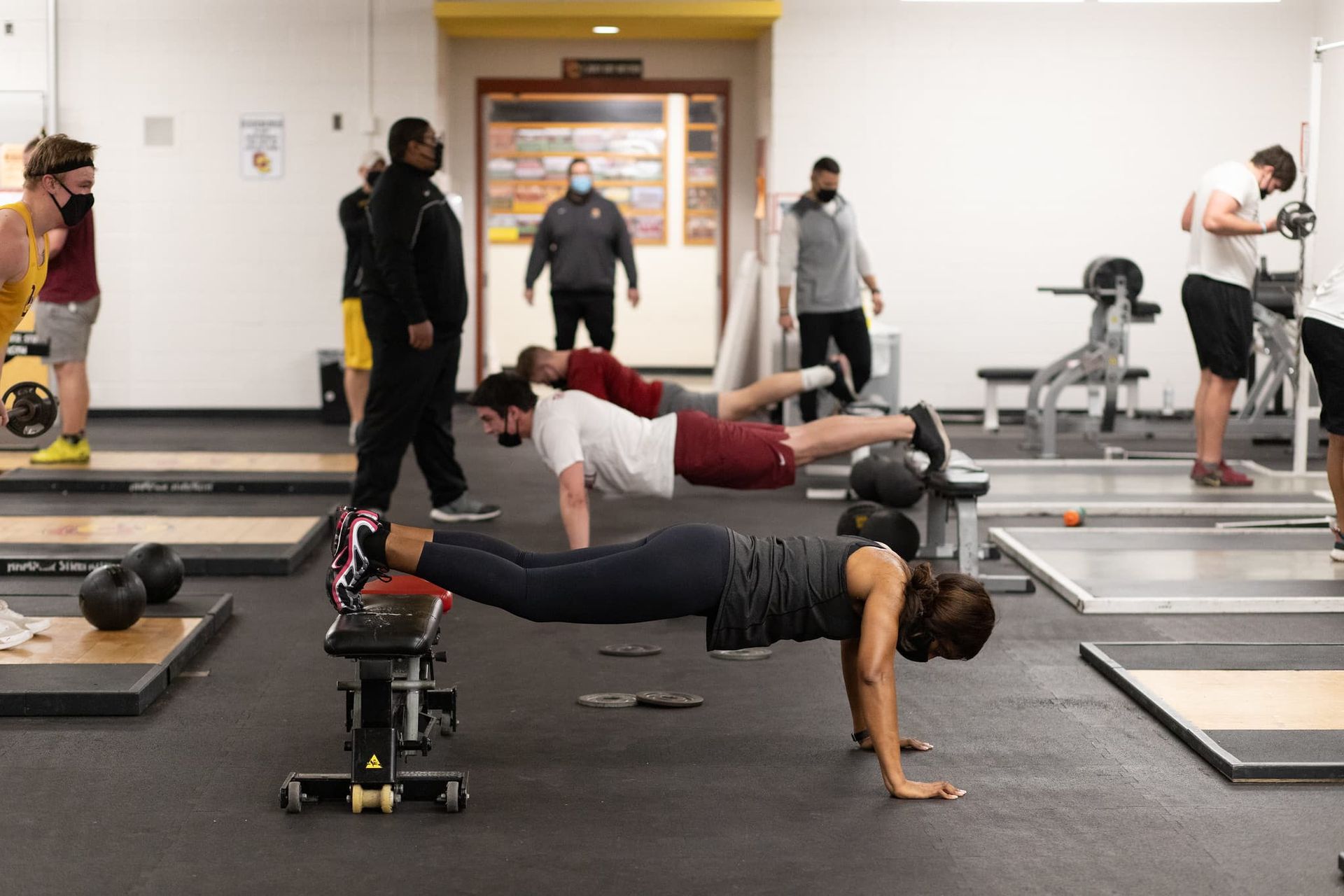 Three people do planks in a gym
