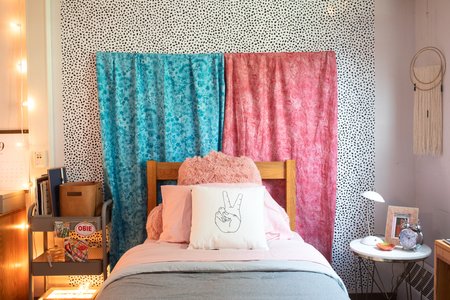 Fabric draped over a wooden stick creates a headboard for a bed.