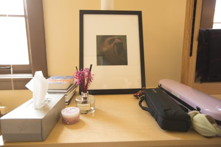 A picture, bottle of scented oil, instrument case, and candle sit in a grouping on a table.