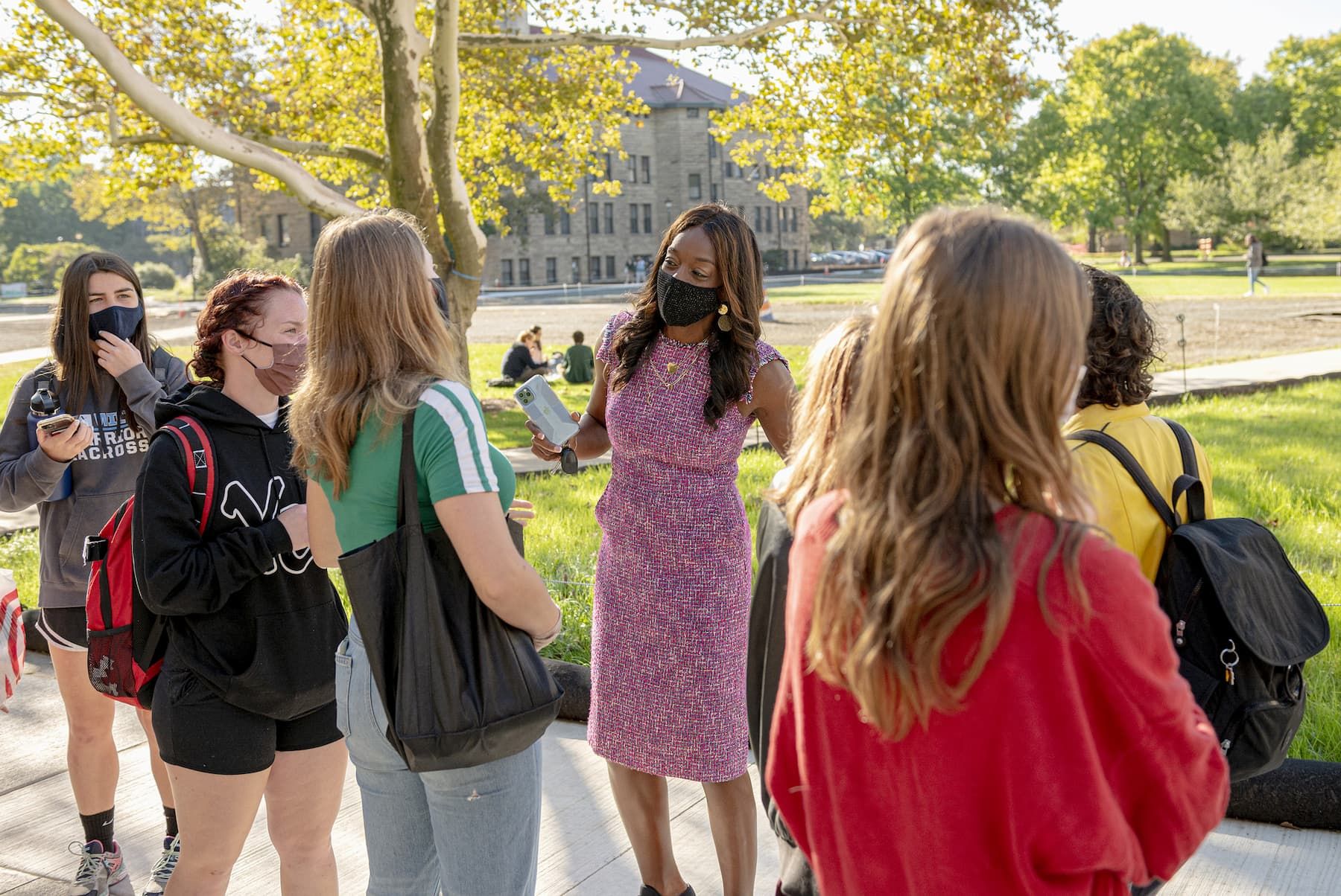 A woman talks to a small group of students.