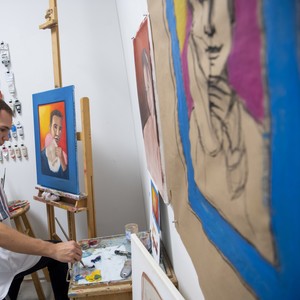 A student works on a painting in a studio.