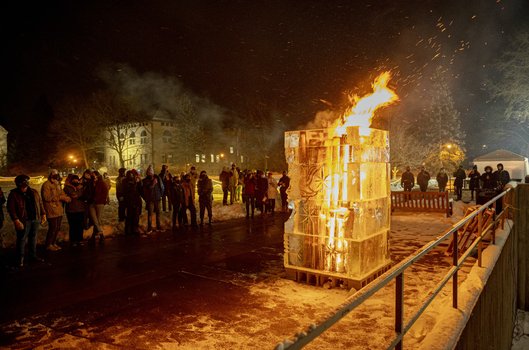 People stand around a burning ice tower.