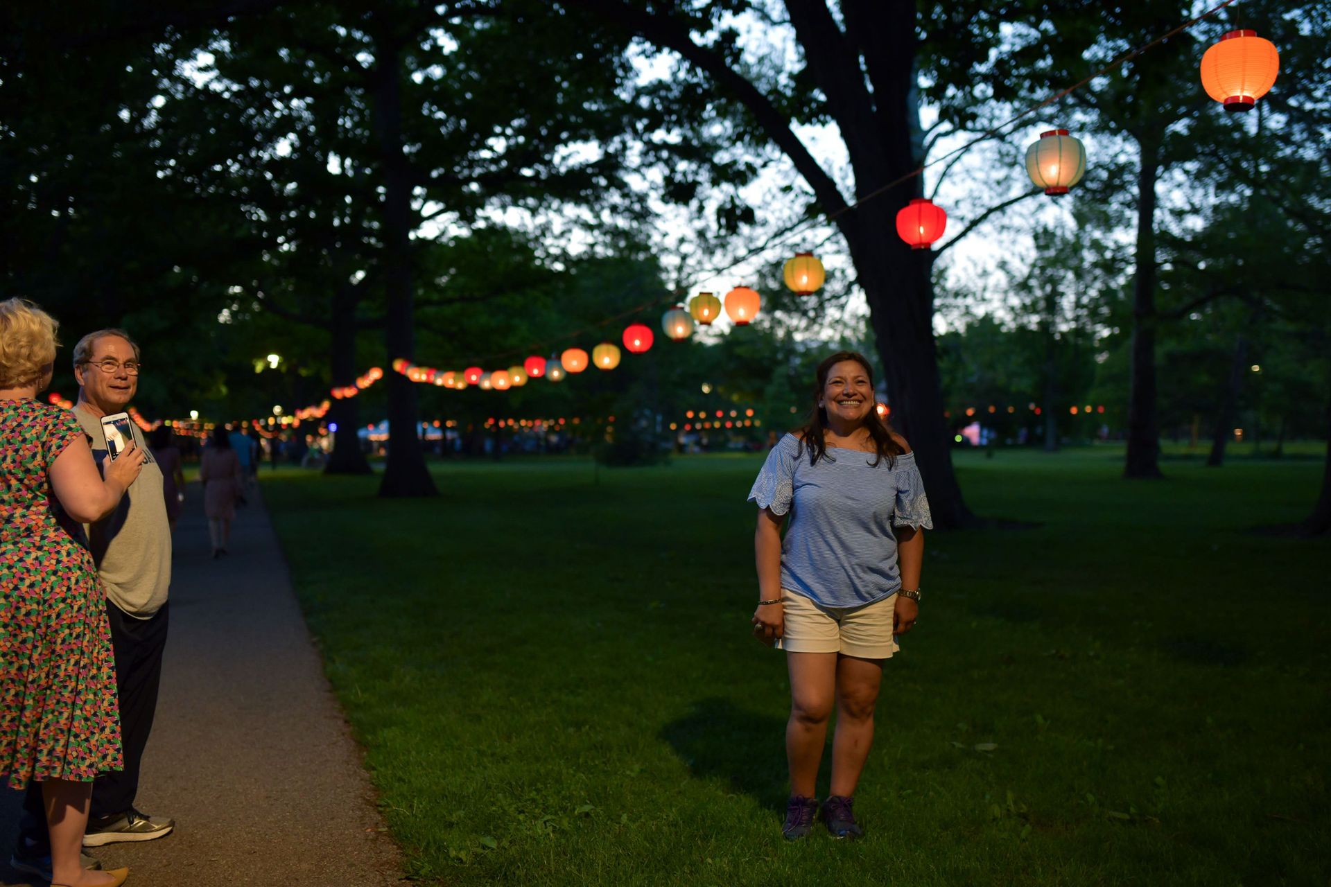 A girl poses for a picture while standing under a lantern
