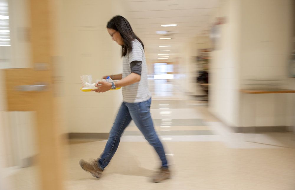 Student walking with a lab tray.