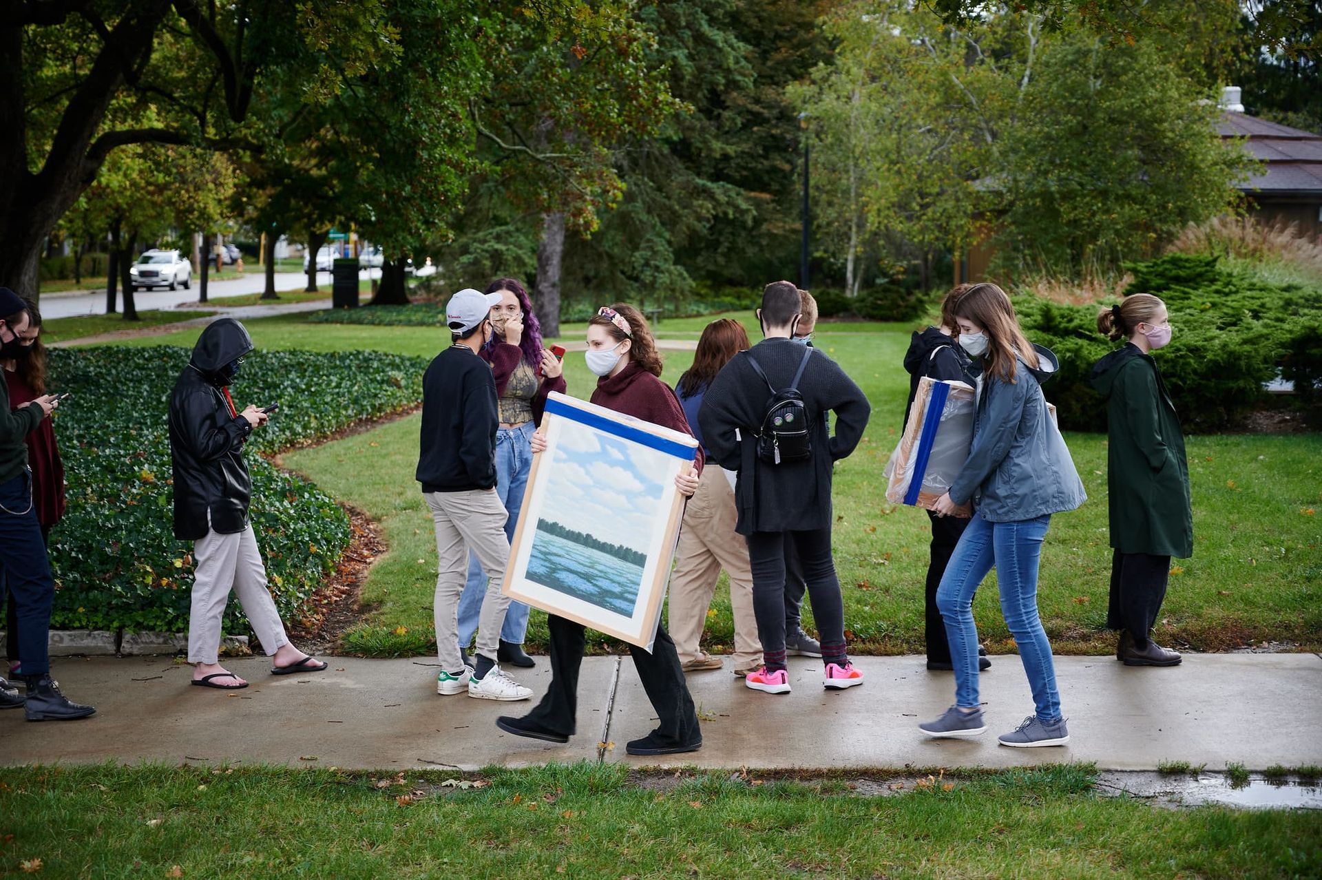 Students carrying large pieces of artwork on canvas.