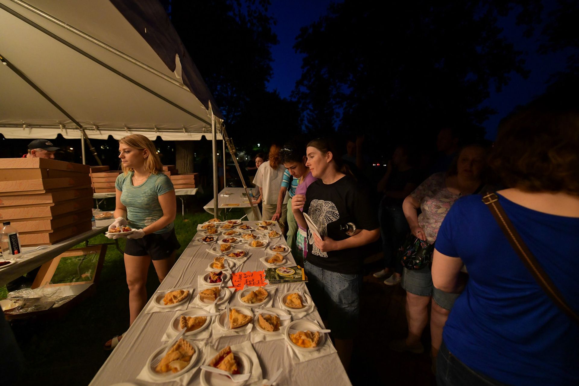 People in line for slices of pie at night.