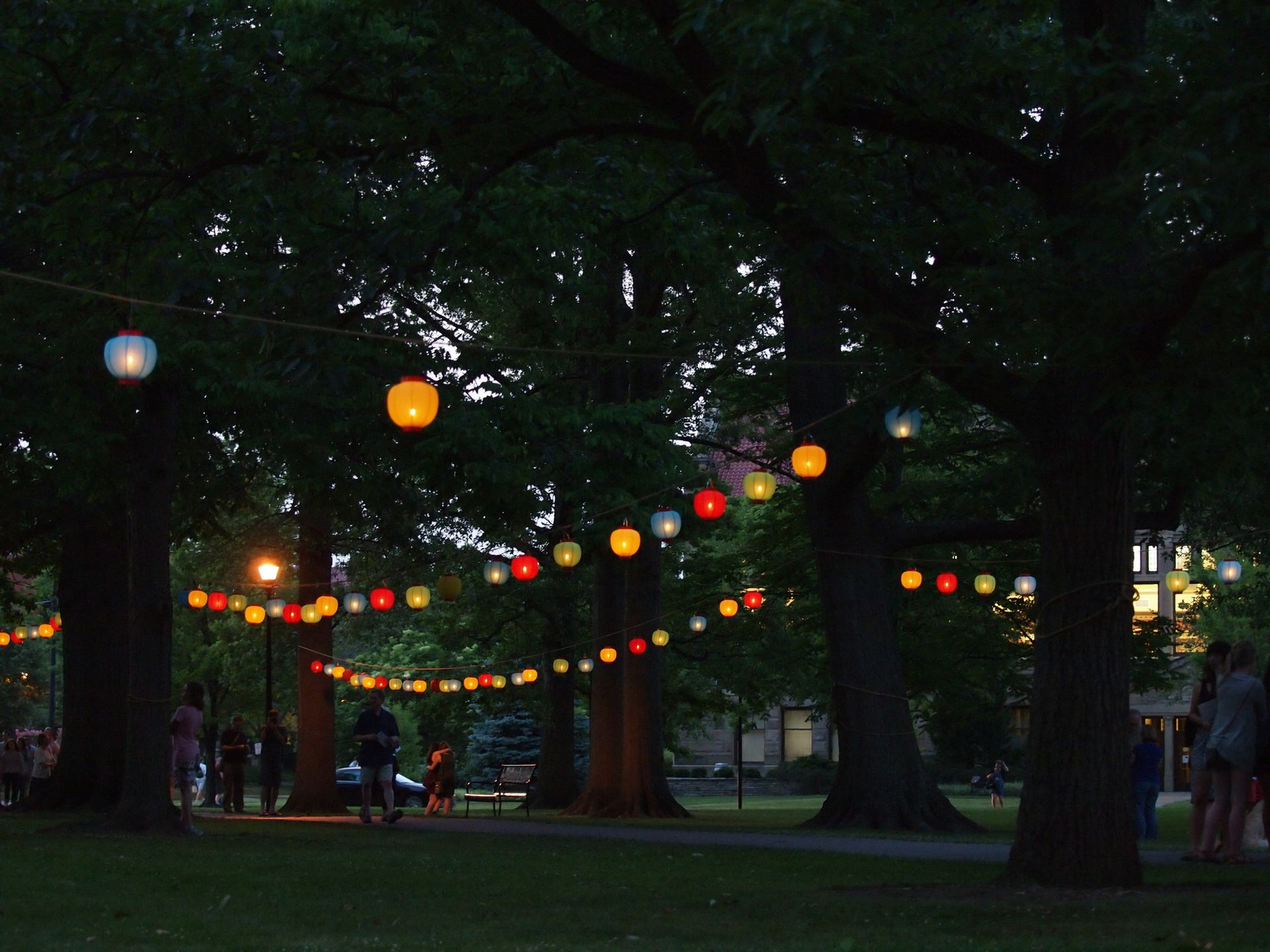 People walk under hanging lanterns