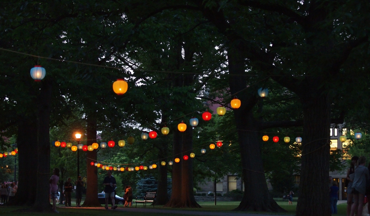 People walk under hanging lanterns