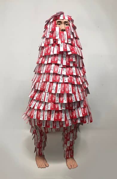 A tall clay person drenched in name tags with different names