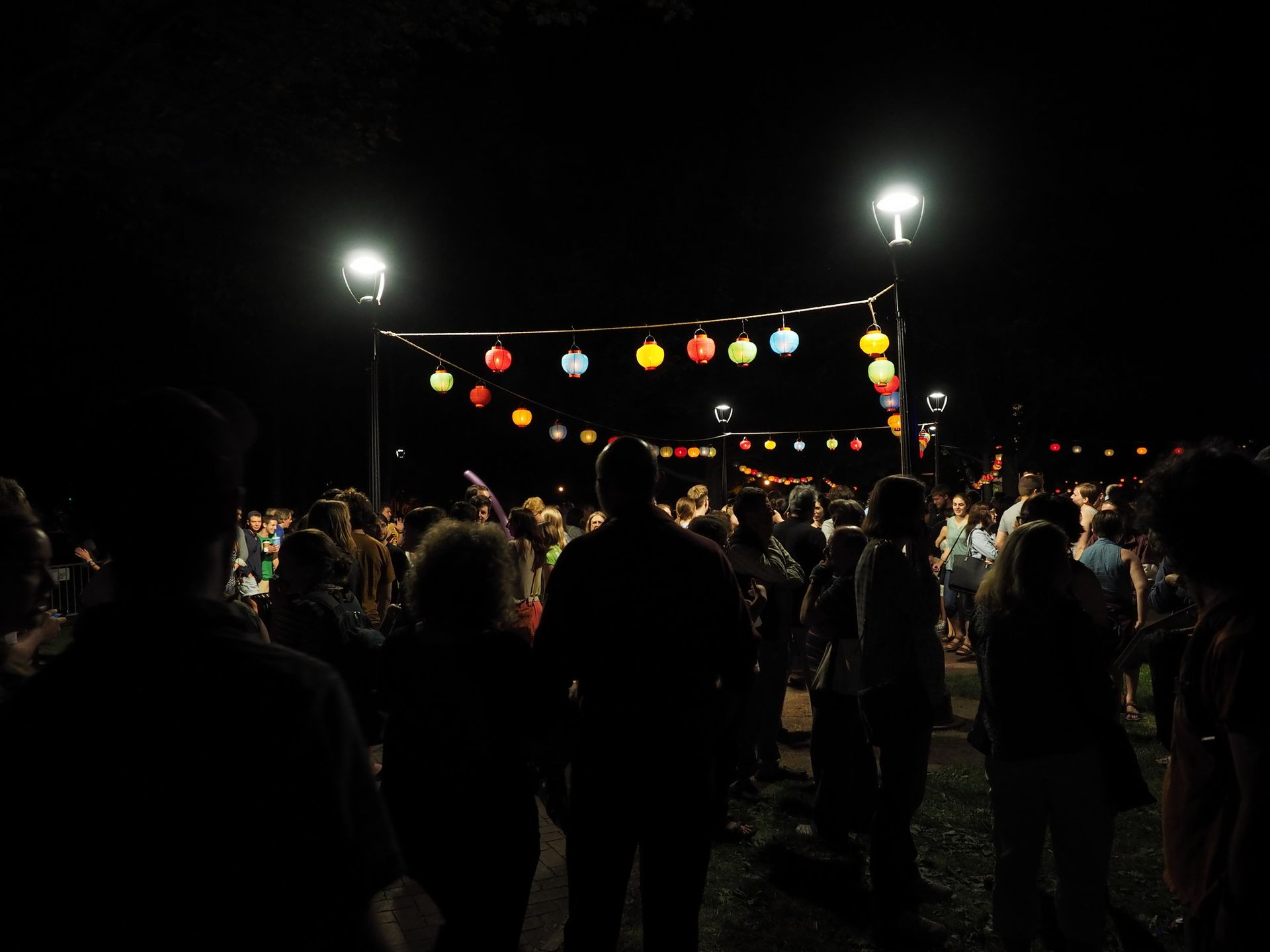 Hanging lanterns forma square and people walk underneath and around it.