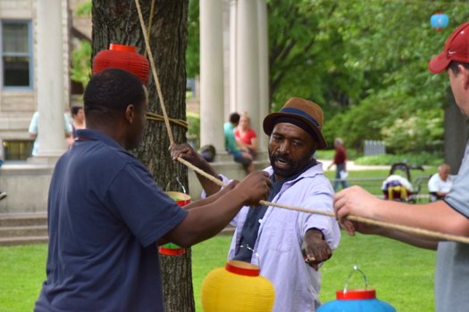 Three men hang lanterns on trees.