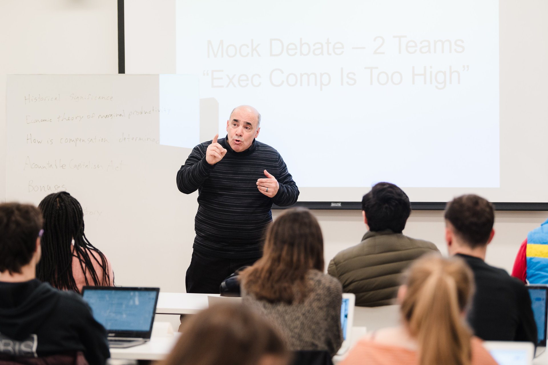 A teacher leads a discussion in front of a classroom of students.