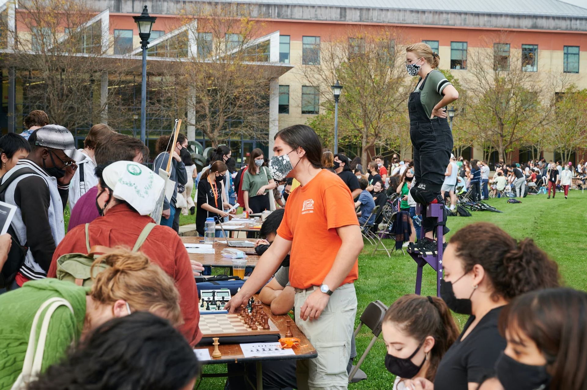 People visit representatives at tables set up in a large field.