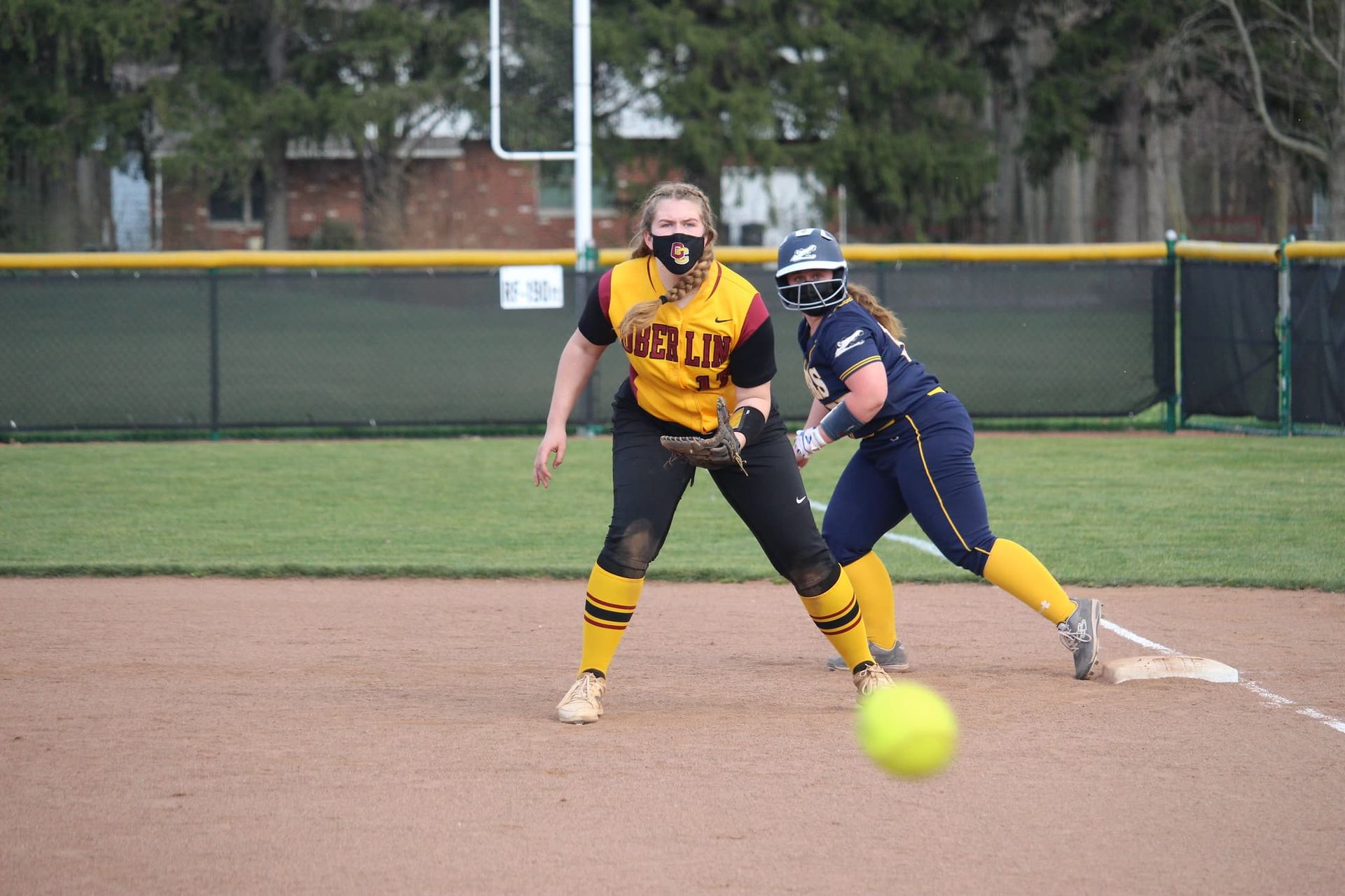 A softball is thrown at a catcher.