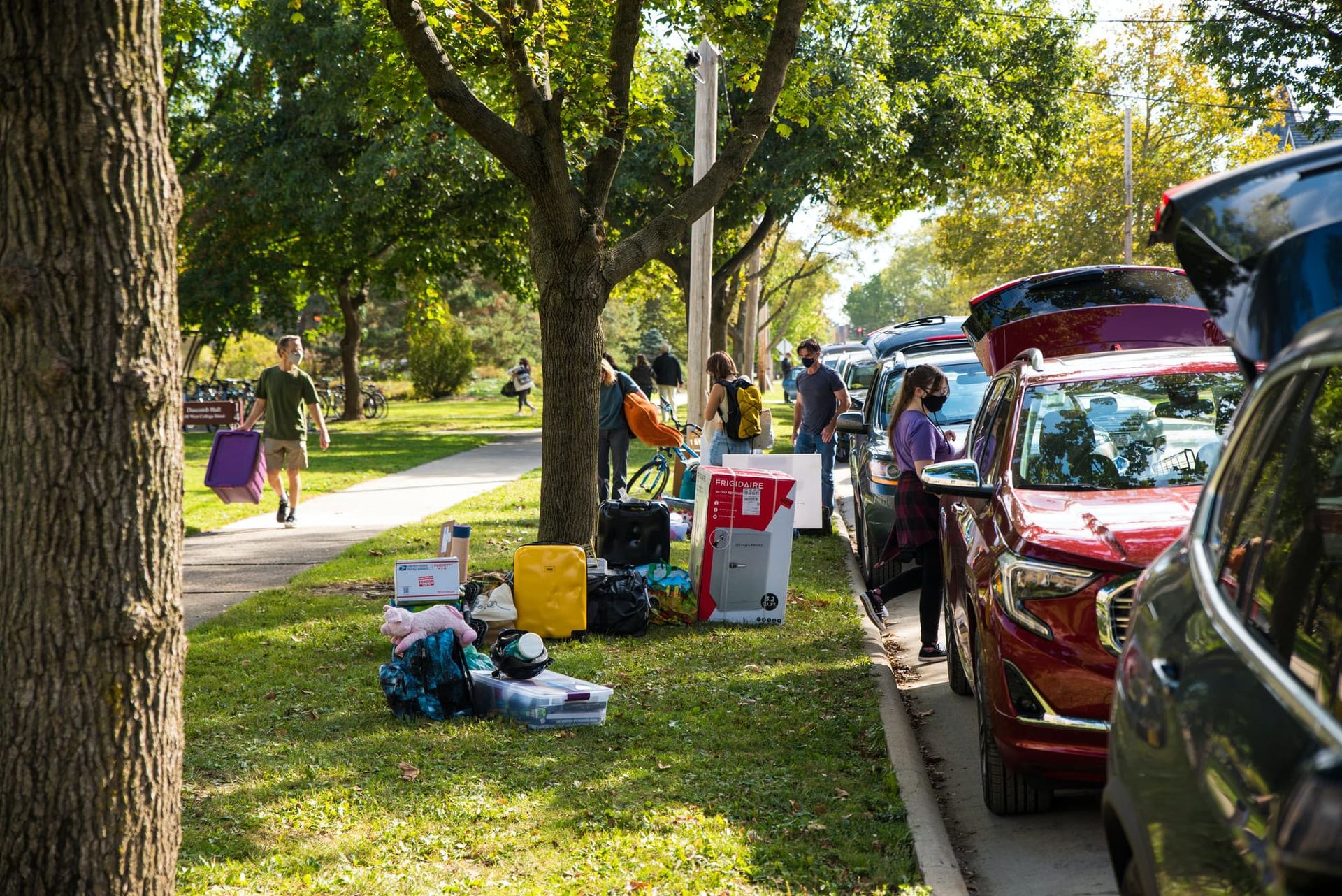 A long row of cars and people unpacking boxes.