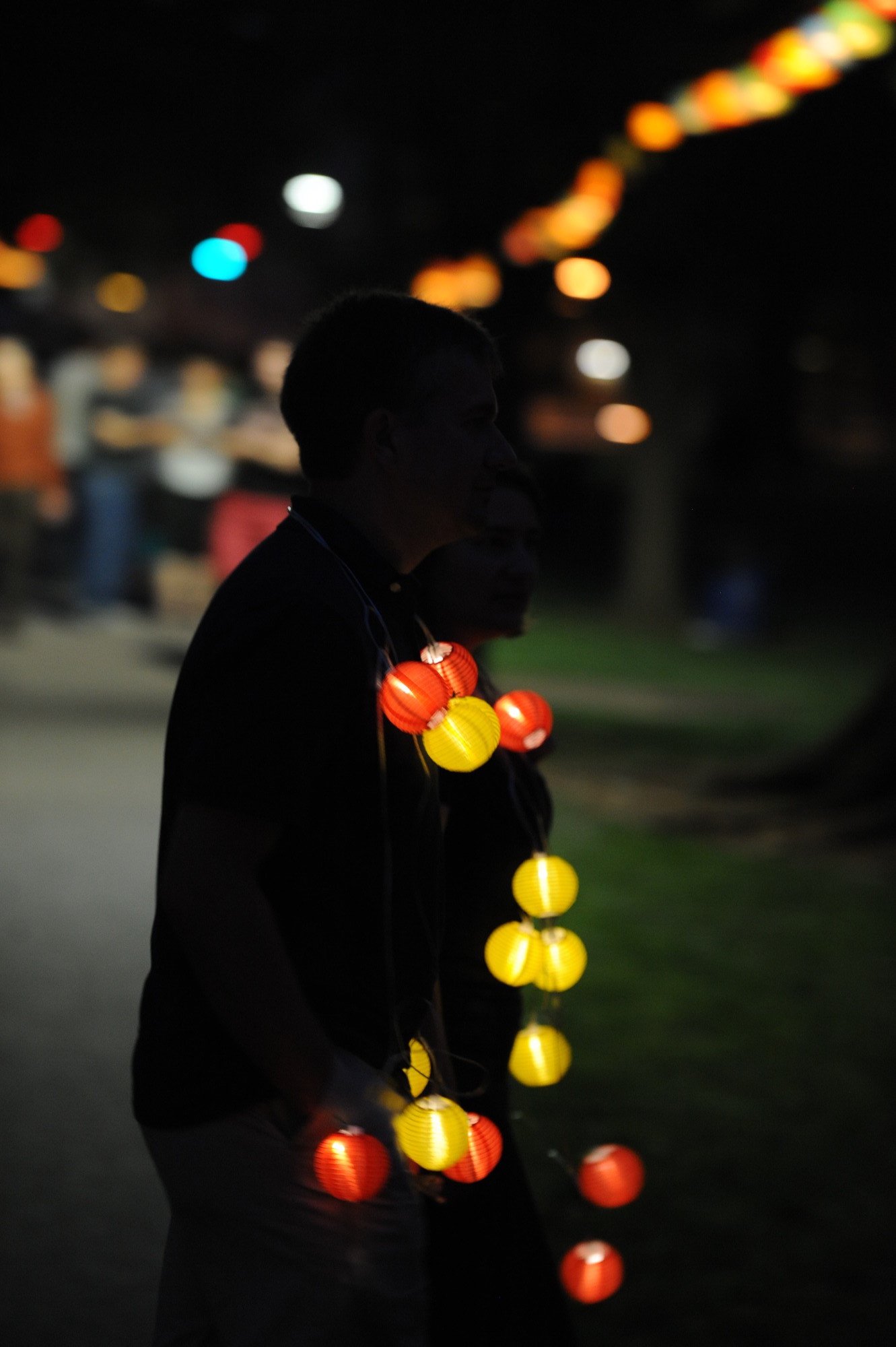 A person wearing a lighted lantern necklace in the dark