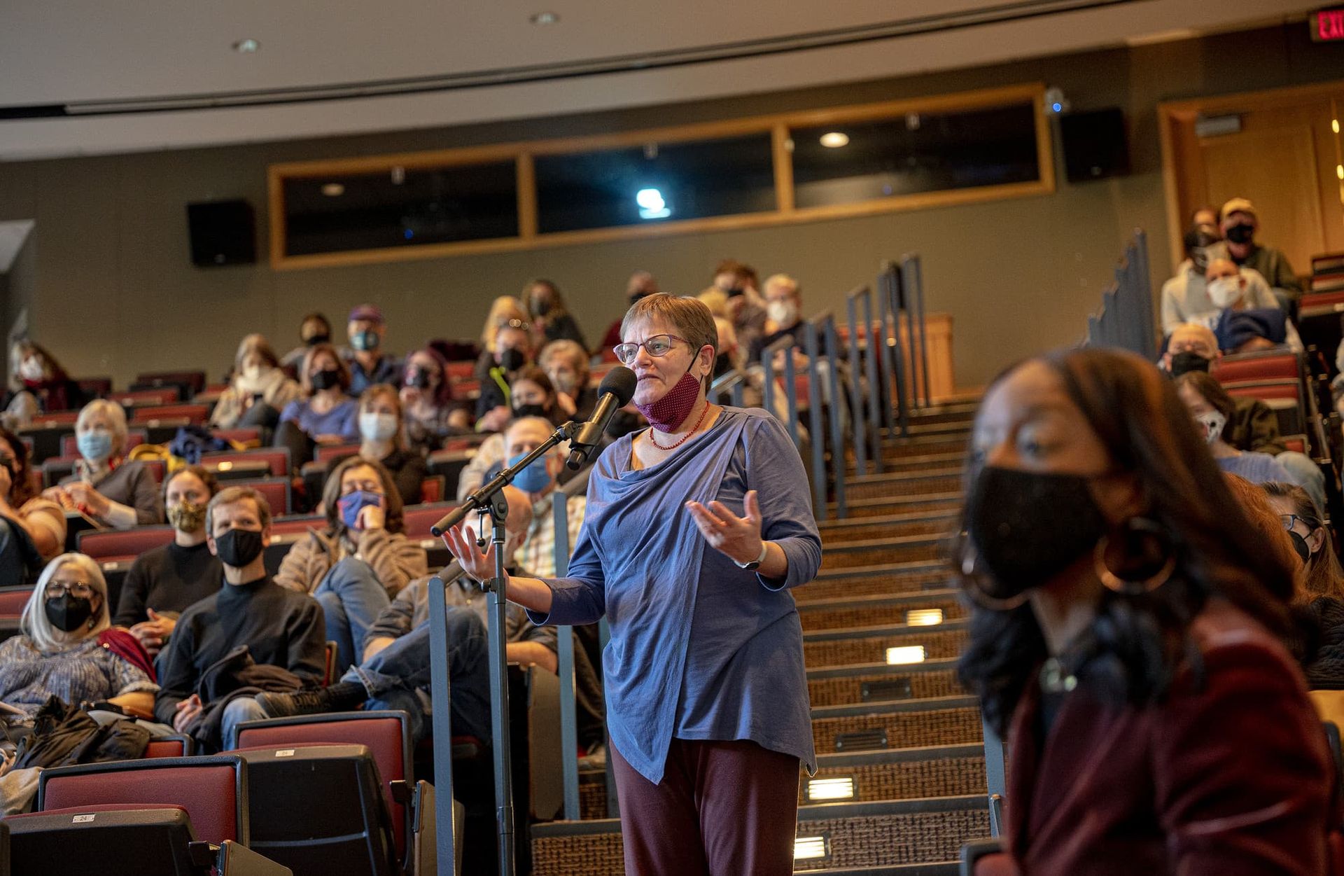 A woman in an audience speaks into a microphone