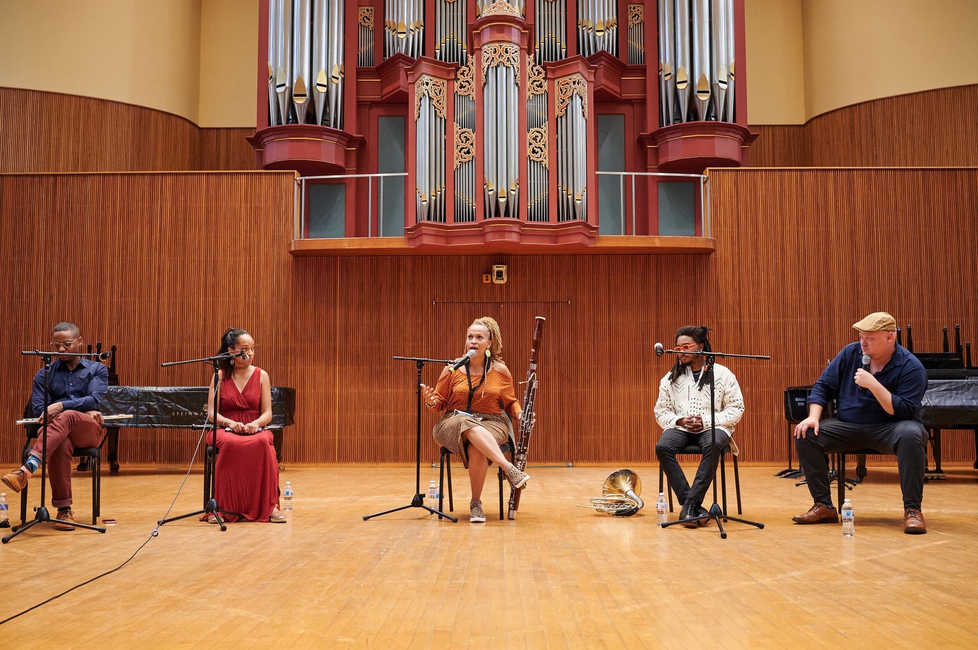 A five member winds band sit on a large stage.